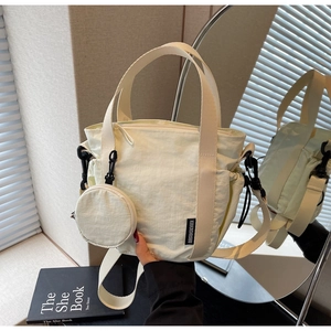 Detail of beige nylon tote bag with small coin purse and KAKADAISHU woven label
