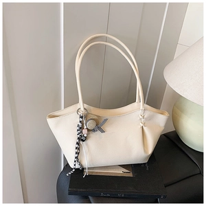 Detail shot of cream leather tote bag with lychee texture and ribbon charm accessory