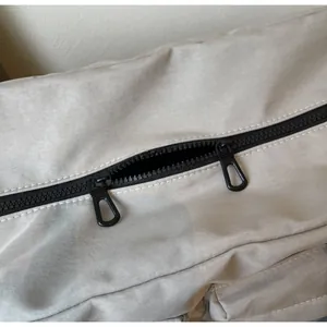 Detail of smooth double metal zippers on light gray travel bag with nylon texture