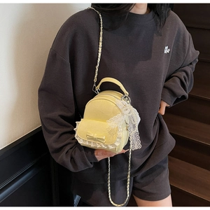 Détail du mini sac à dos jaune avec bordure en dentelle et nœud sur l'escalier