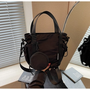 Detail of black nylon bucket bag with detachable coin purse on a sunlit windowsill