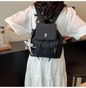 Detail of black nylon backpack with white star print and silver star bag charm