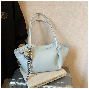 Close-up of mint blue tote bag with lychee grain texture and stylish charms on suitcase