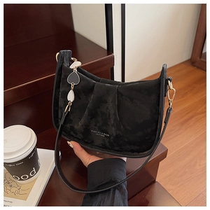 Détail du sac hobo en daim noir avec texture plissée et chaîne décorative en cœur