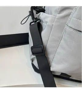 Detail of adjustable black nylon shoulder strap on light grey travel bag with hook