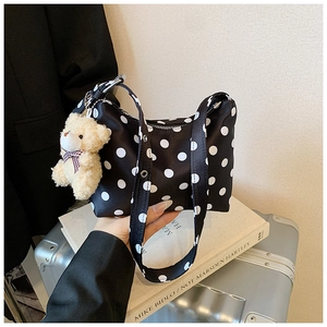 Detailansicht der gepunkteten Schultertasche mit Reißverschluss und Bärenanhänger