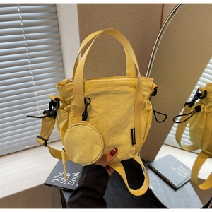 Detail of yellow nylon bucket bag with round coin purse and adjustable strap in mirror view
