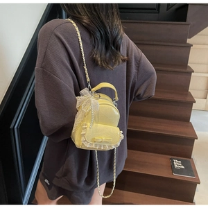 Détail d'un mini sac à dos jaune avec dentelle, perles et nœud sur mannequin