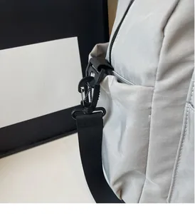 Close-up of durable black plastic hook and nylon shoulder strap on the grey travel bag