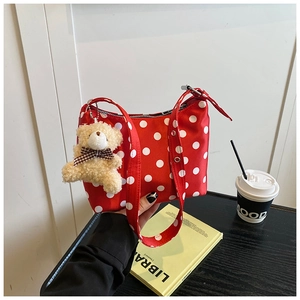 Detail of red polka dot canvas tote bag featuring a cute beige plush bear pendant