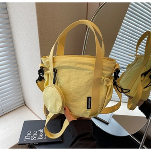 Detail of yellow nylon bucket bag featuring pleated texture and mini coin purse