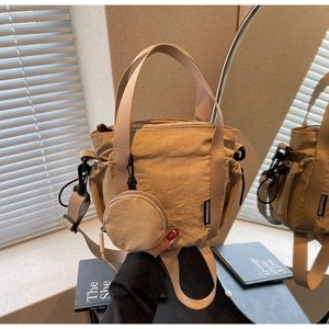 Detail of khaki nylon tote bag with mini round pouch and detachable strap on indoor surface