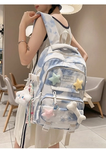 Detail view of tie-dye backpack featuring cute plush stars and bone charms in a cozy cafe