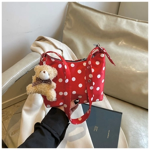 Detailaufnahme der roten Polka-Dot-Hobo-Tasche auf dem Sofa mit süßem Bärenanhänger