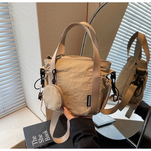 Detailed view of beige nylon bucket bag with logo patch, drawstring pocket, and coin purse