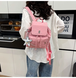 Pink polka dot backpack with silver star pendant shown on model in home setting