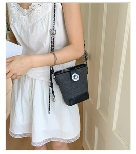 Detail of tweed and leather bucket bag with silver round twist lock and chain strap