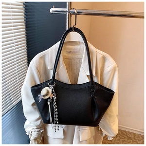 Detail of black pebbled leather tote bag with a mini straw hat and ribbon charm