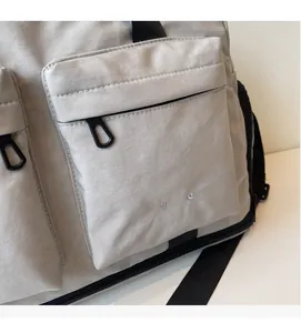 Close-up of gray travel bag fabric with embroidered logo and black zipper detail