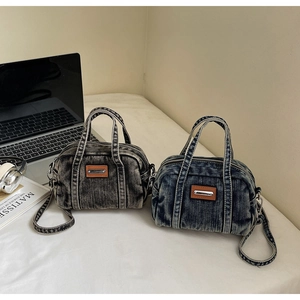 Close-up of distressed denim handbags in blue and black with brown leather labels