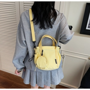 Detail of yellow canvas bucket bag with mini round coin purse shown on a model
