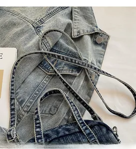 Detail view of adjustable denim shoulder strap with metal buckle on blue wash handbag