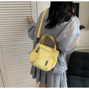 Detail of yellow canvas bucket bag with adjustable wide strap and round coin purse