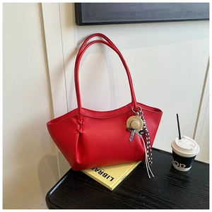 Detail of red pebbled leather tote bag featuring woven stitching and luxury charm