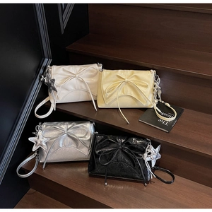 Detail of bow-knot shoulder bags in white, yellow, silver and black on wooden stairs