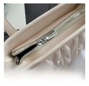 Close-up of silver zipper hardware on quilted cream leather bag with crystal accents