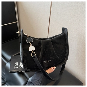 Détail du sac seau en velours noir avec texture plissée et pendentif coeur en métal
