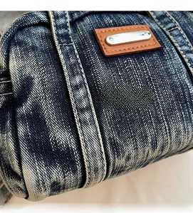 Detail showing washed denim fabric texture with white stitching and leather patch