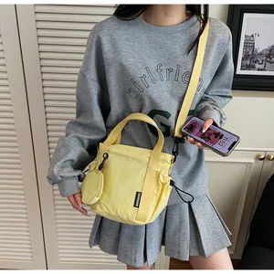 Detail of yellow nylon bucket bag with drawstring closure and mini round coin purse charm
