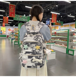 Detail of tie-dye backpack with plush star charms and cloud pendant in a lifestyle setting
