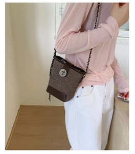 Detailed view of a brown textured bucket bag with leather trim and metal chain strap