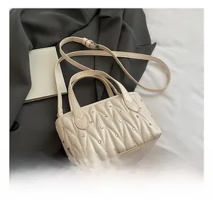 Detail of cream quilted crossbody bag with sparkling rhinestones on grey blazer