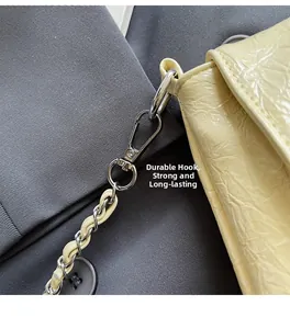 Detail of durable silver metal hook and chain strap on light yellow pleated bag