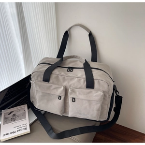 Detail of a large beige travel bag with dual zip pockets and stylish MULAIDISS embroidery