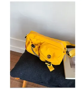 Detail view of bright yellow nylon crossbody bag featuring buckle front pocket on a bench