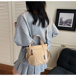 Detail of beige wrinkled nylon bucket bag with round mini pouch and sturdy woven straps