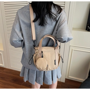 Detail of beige nylon crossbody bucket bag with drawstring closure and small round pouch