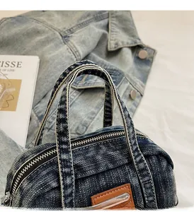 Detailed close-up of sturdy denim top handle and smooth metal zipper on blue wash bag