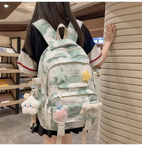 Detail of tie-dye backpack showing plush star patches and cute cloud keychain accessories