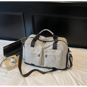 Detail view of large travel duffel bag showing front zip pockets and adjustable shoulder strap