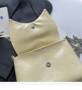 Detail of creamy yellow pleated shoulder bag with silver chain and starfish charm
