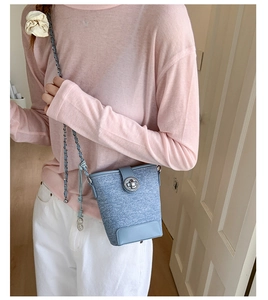 Detail of light blue bucket bag showing textured weave, leather trim, and silver twist lock