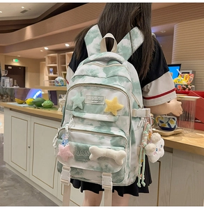 Detail of green tie-dye backpack showing side buckles, multi-zipper pockets and cute charms