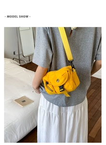 Model wearing a bright yellow crossbody bag with wide strap and side drawstring detail