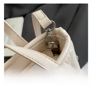 Detailed macro view of cream quilted faux leather with silver metal swivel hooks