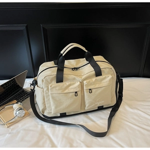 Beige canvas travel bag with laptop and headphones on bed showing lifestyle usage